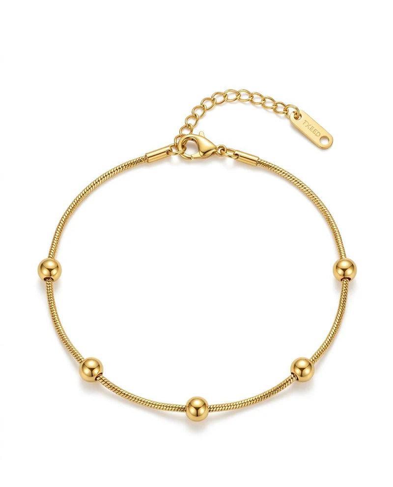 A gold-plated snake chain bracelet with five evenly spaced round bead accents, a lobster clasp, and an adjustable extension chain with a tag, shown on a plain white background.