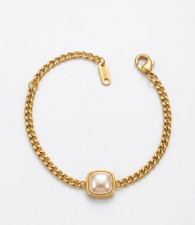A gold chain bracelet featuring a central square bezel-set pearl, photographed on a clean white background.