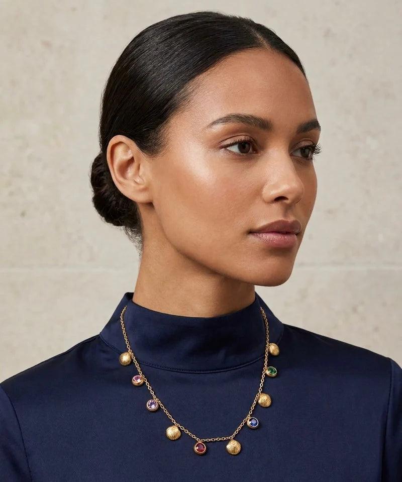 Woman wearing a necklace with colorful beads against a neutral background