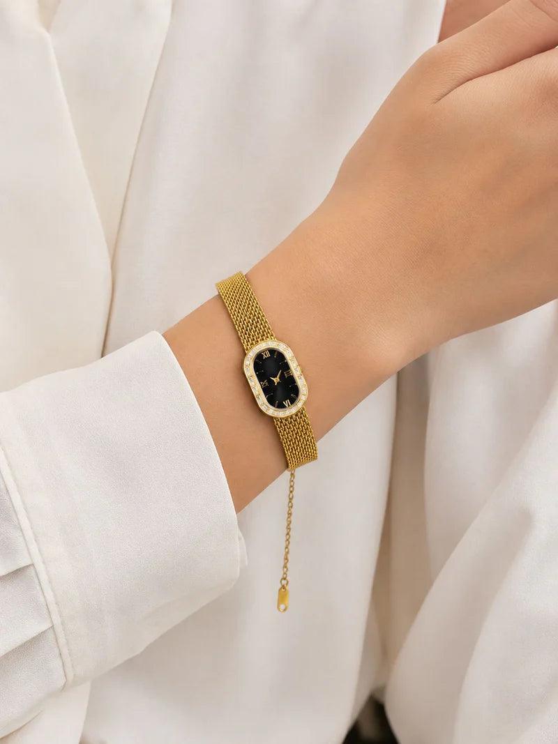 Gold bracelet with a black stone on a wrist against a white background