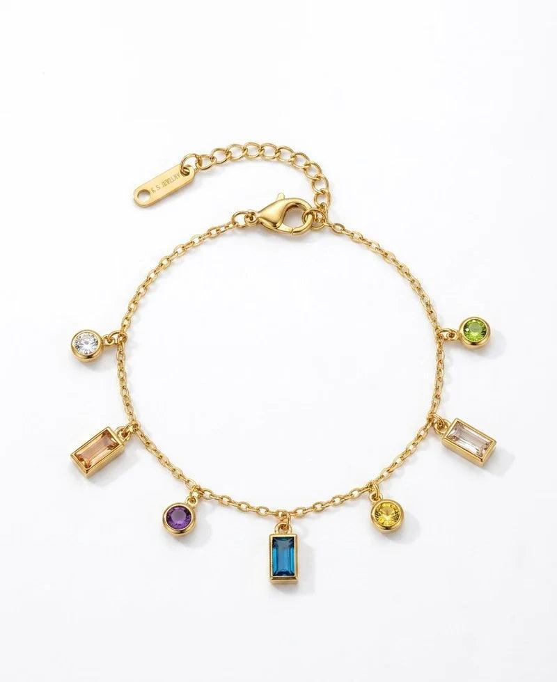 A gold charm bracelet with multiple colorful gemstone charms, displayed on a clean white background.