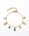 A gold charm bracelet with multiple colorful gemstone charms, displayed on a clean white background.