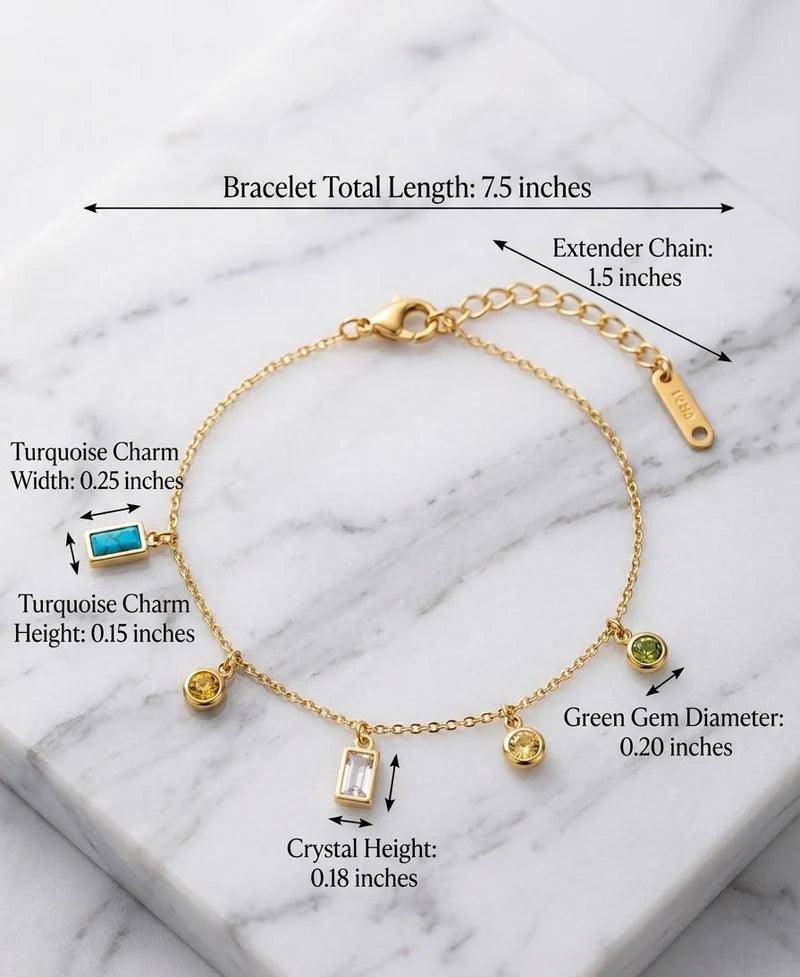 Gold bracelet with charms on a marble background, showing measurements.