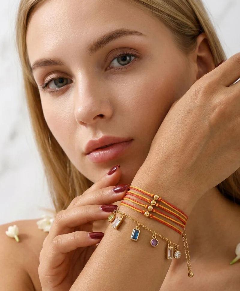 Woman wearing multiple bracelets with charms on a blurred background