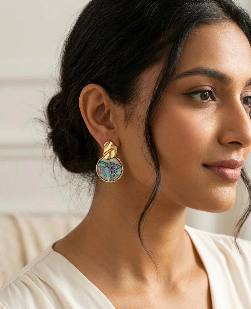 Woman wearing gold earrings with a neutral background