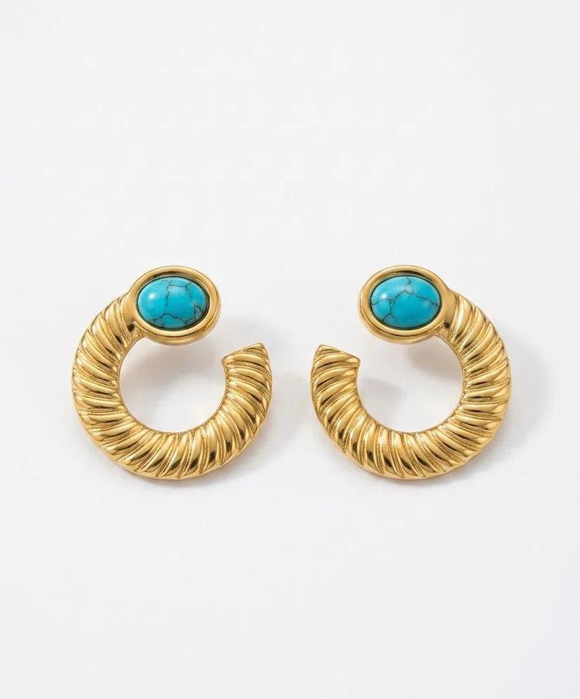 A pair of gold-toned twisted hoop earrings with oval turquoise stone accents, displayed on a clean white background.