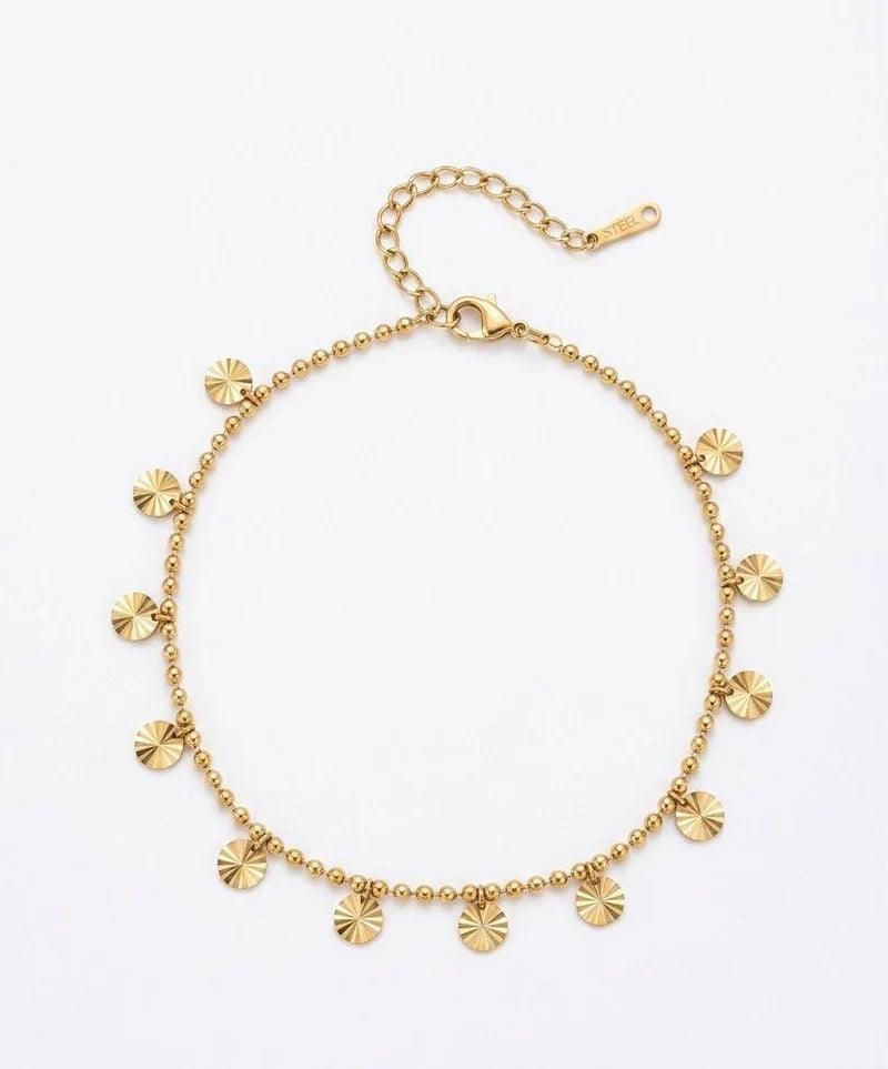 A gold-toned beaded necklace with small sunburst disc charms, displayed on a clean white background.