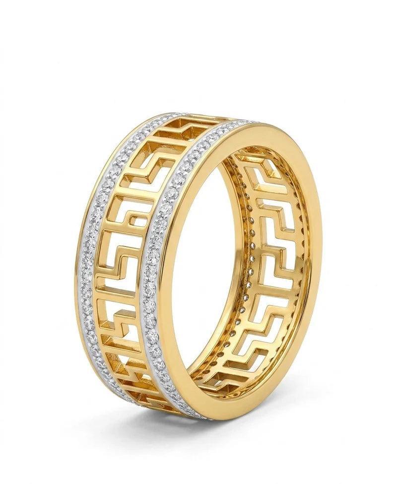 A yellow gold band ring featuring a Greek key pattern with rows of small clear stones, shown on a clean white background.
