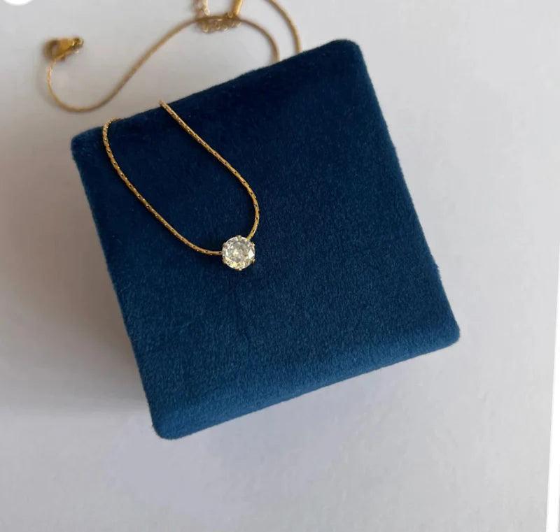 Gold necklace with a diamond pendant on a blue cushion