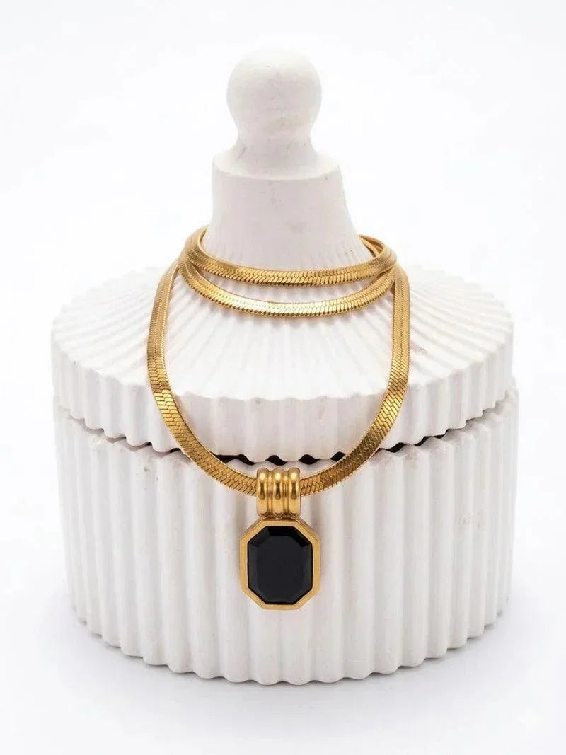 Gold necklace with a black pendant on a white jewelry box