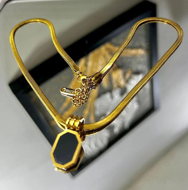 Gold necklace with a pendant on a reflective surface