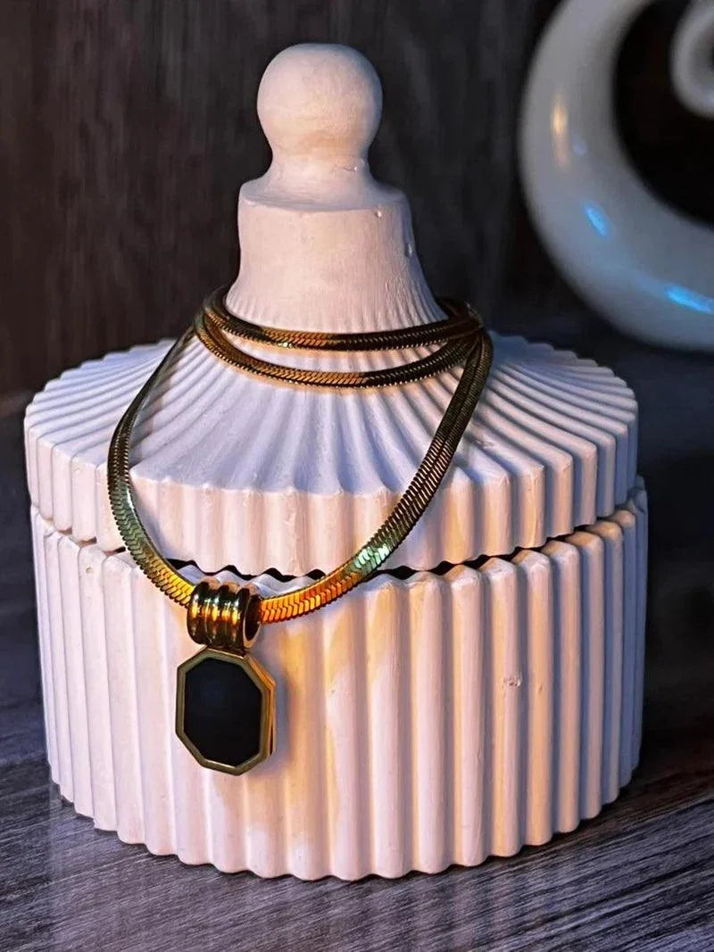 Necklace with a pendant on a decorative white container against a dark background