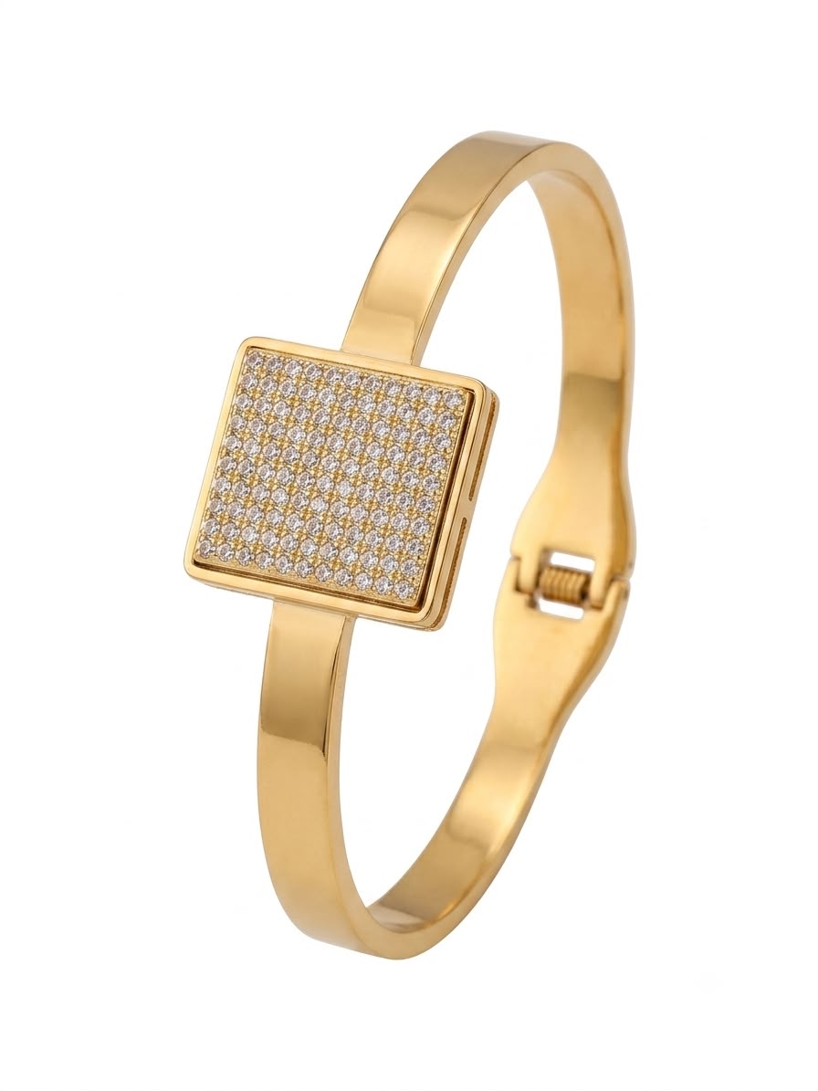 A gold-plated bangle bracelet featuring a square pavé-set bezel with small clear stones, shown on a plain white background.
