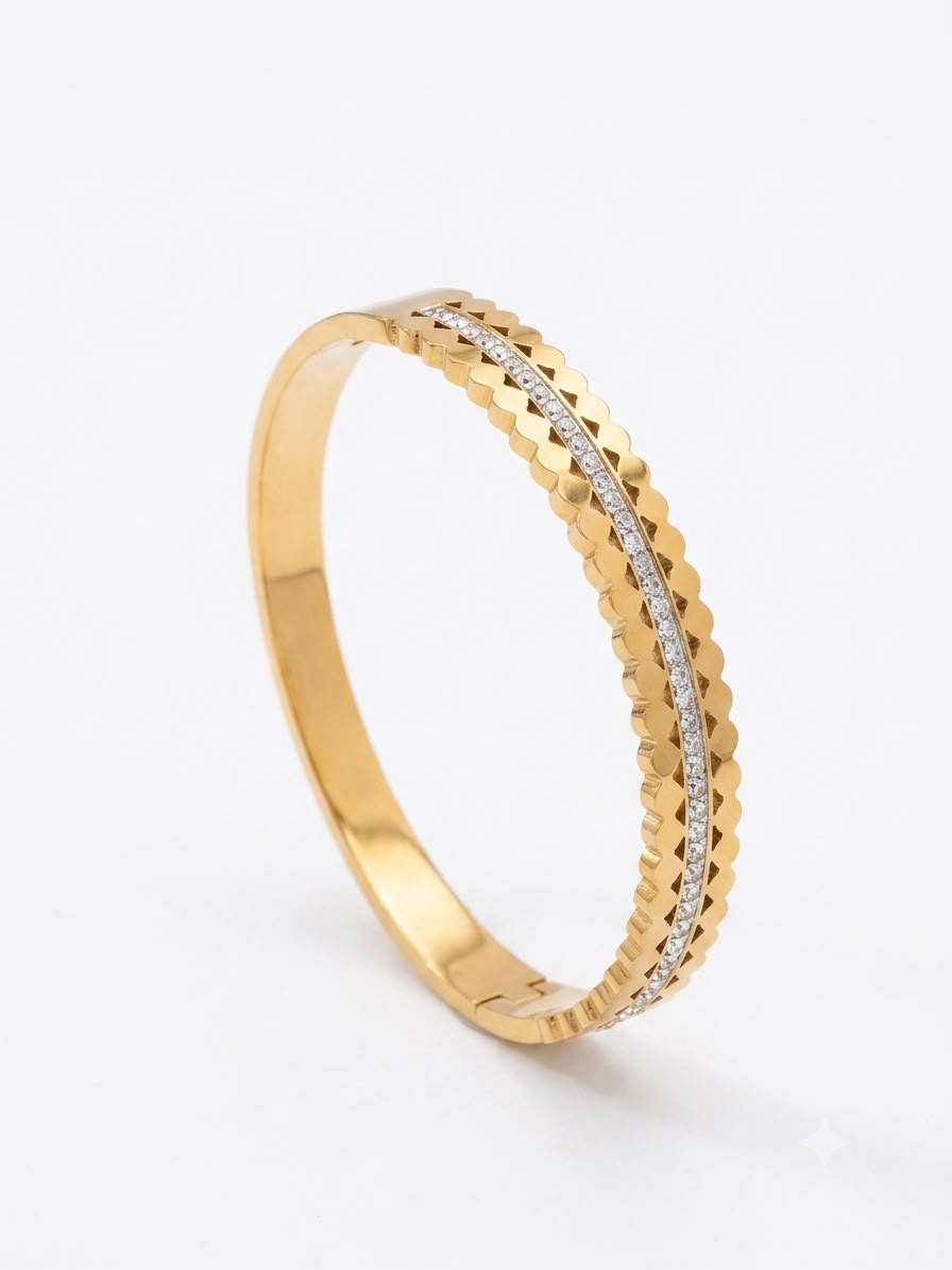 A gold bangle bracelet with a textured, diamond-cut outer band and a central channel set with small clear stones, shown on a clean white background.