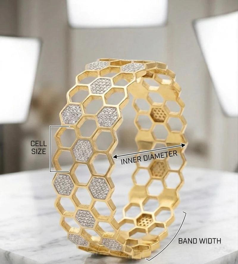 Gold honeycomb bangle bracelet with pavé-set clear stones, shown on a marble surface with overlaid measurement labels for cell size, inner diameter, and band width.