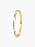 A slim gold bangle bracelet featuring a channel-set row of clear baguette-cut stones along one side, shown on a clean white background.