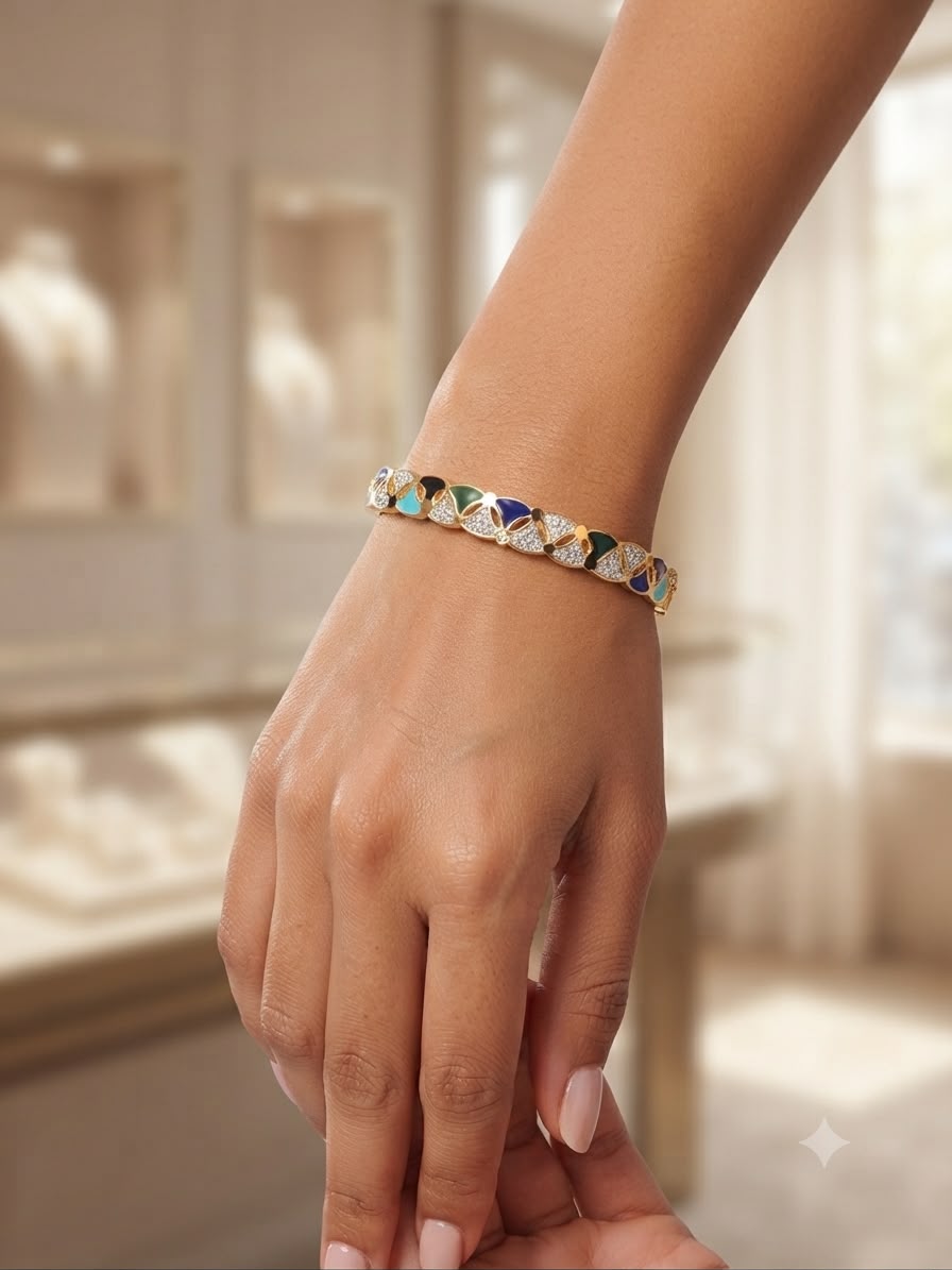 A close-up of a person's hand and wrist wearing a delicate silver-toned beaded bracelet with colorful faceted crystal segments in blue, green, orange, and yellow, set against a softly blurred jewelry store background.