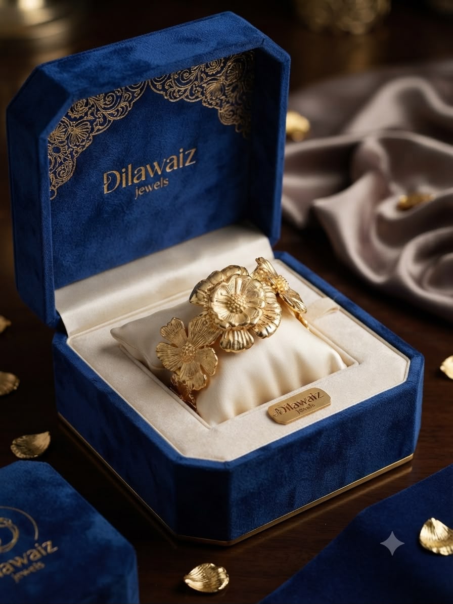 A gold floral cuff bracelet displayed inside an open blue velvet jewelry box with gold detailing. The box lid is printed with the brand name 'Dilawaiz Jewels'.