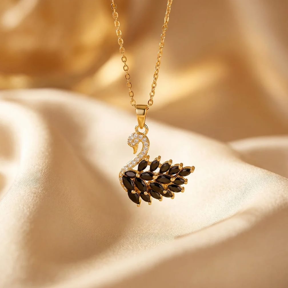Gold necklace with a swan-shaped pendant on a beige fabric background