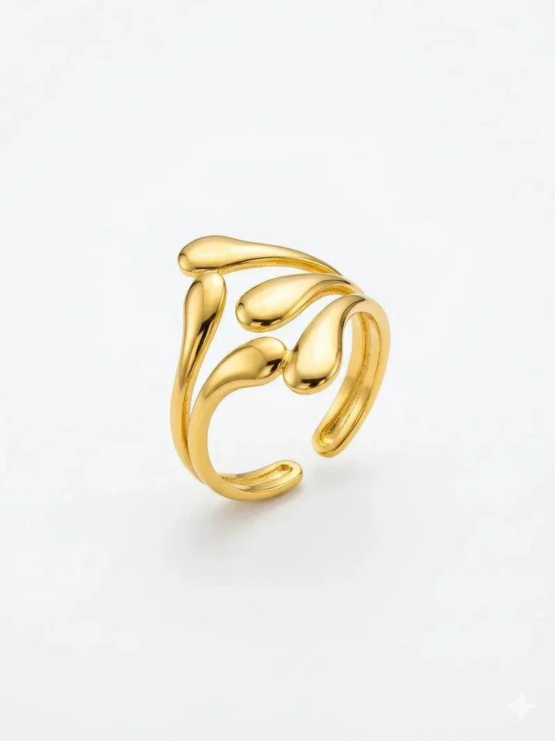 A gold-toned open ring with a sculptural, flowing leaf-like design, photographed on a clean white background.