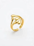 A gold-toned open ring with a sculptural, flowing leaf-like design, photographed on a clean white background.